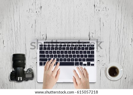 Person using laptop, placed on antique wooden table, with coffee and modern camera beside. Empty header for text input
