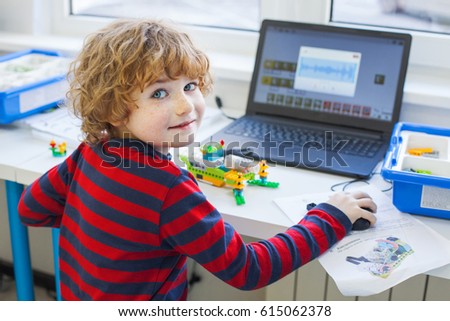 boy in robotics school makes robot, managed from the constructor, boy programming robot,  pupils in science lesson studying robotics, education, science and people concept, children, technology Royalty-Free Stock Photo #615062378