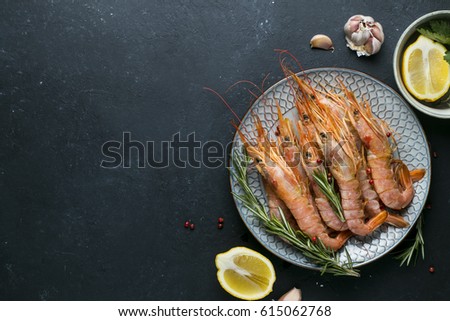 Large red Argentine shrimp (langoustine) on the plate and ingredients on a black background
