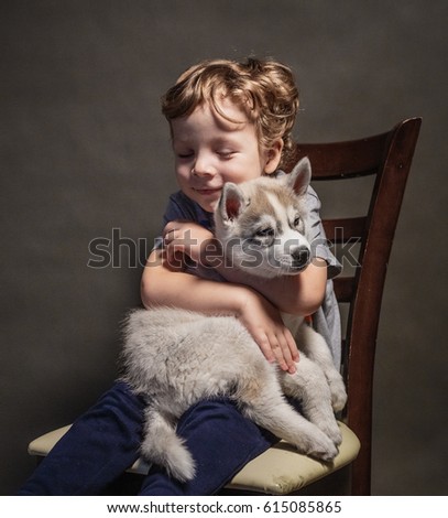 Beautiful baby with a husky puppy sitting on his hands