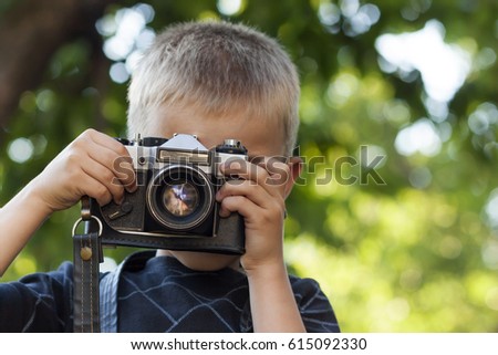 Cute little happy boy with vintage photo camera outdoors