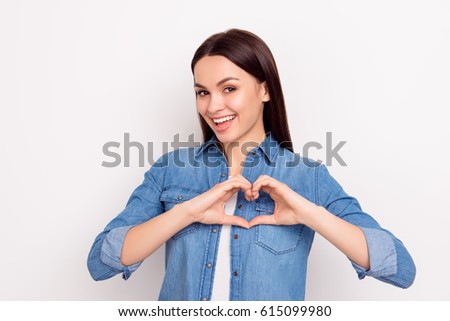 Cute beautiful girl in love making heart with fingers and smiling