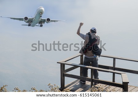 The tourist taking photo with the airplane on blue light sky background