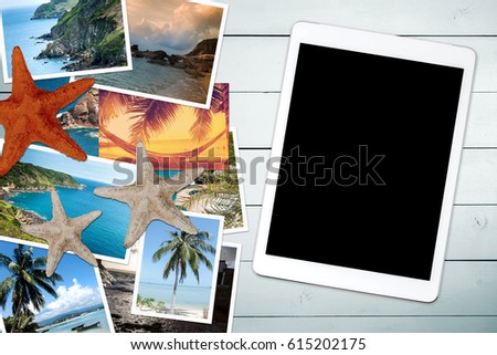 Vacation pictures on a wooden table and blank screen tablet. View from above.