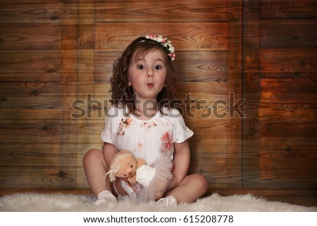 Little girl with curly hair, having fun while posing at the camera
