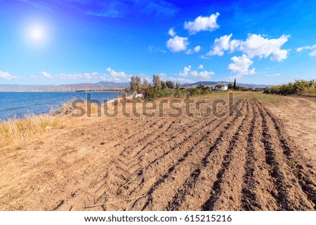 plowed field near the sea. Sun in blue sky