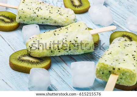 Popsicles on a stick of kiwi and lime on a wooden table