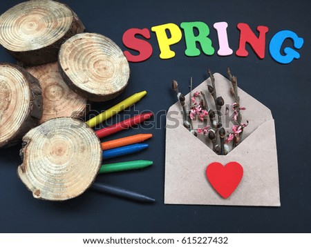spring envelope with buds and flowers. wooden letters with color pencils and wooden slices on black chalkboard 