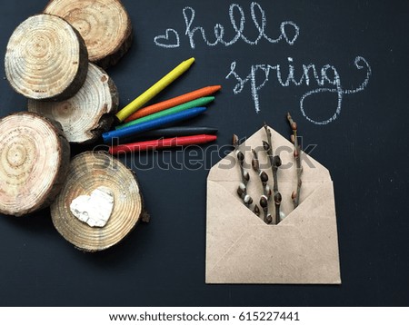 hello spring with heart. spring wooden letters with color pencils and wooden slices on black background