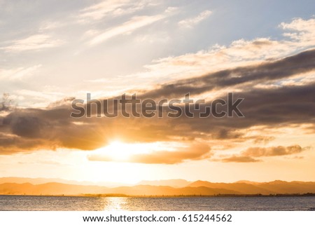 Bright sunset behind ominous dark clouds above the beach, Gisborne, New Zealand.