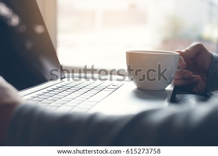 Casual man sitting on the floor at home drinking hot coffee and relaxed using laptop computer, man internet browsing on laptop computer, morning news update, modern lifestyle concept Royalty-Free Stock Photo #615273758