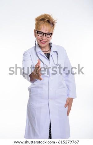 Studio shot of happy senior Asian woman doctor smiling while giving handshake and wearing eyeglasses against white background