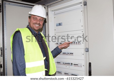 Electrician builder engineer worker in front of fuse switchboard with helmet for security