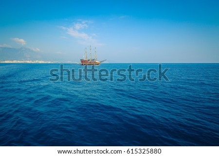 Morning sea with boat on the horizon. Aged photo. Sailing ship profile. Toned image. Sunbeams on the sea surface. Calm Sea with a Sailing Vessel. Cirali, Antalya Province, Turkey.