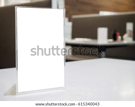 Mock up menu frame on table in the cafe restaurant, acrylic stand with white paper