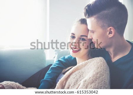 Loving young couple hugging and relaxing on sofa at home
