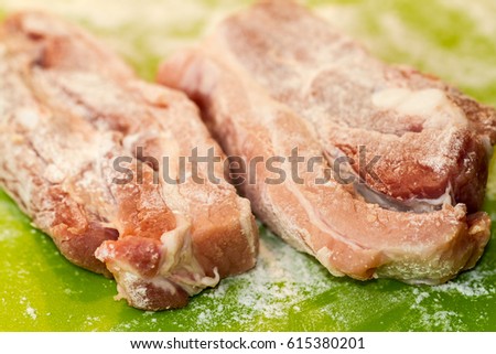 Close Up of Two Salted and Seasoned Pork Loin Chops on Green Background Surface, in Selective Focus with Copy Space