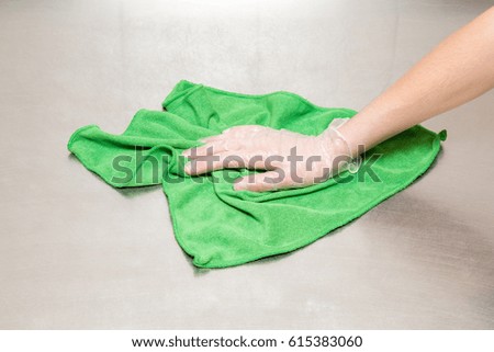 Hand in protective glove with rag cleaning kitchen equipment in the professional kitchen. Stainless steel surface. Early spring cleaning or regular clean up.