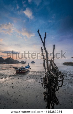A sampan with a rope on a beach facing the sunrise on the left side