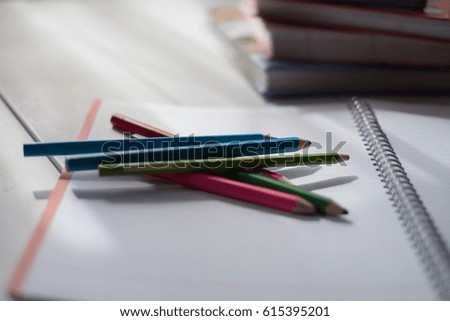 colored pencils with a notebook and books on a white wooden table