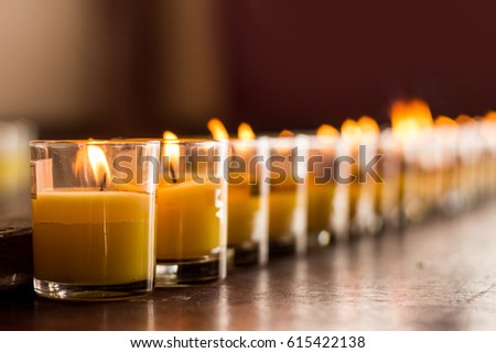 close up burning candle in glass for praying in temple Buddhism