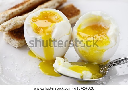 Two soft boiled eggs with toast soldiers over a white plate. Extreme shallow depth of field with selective focus.