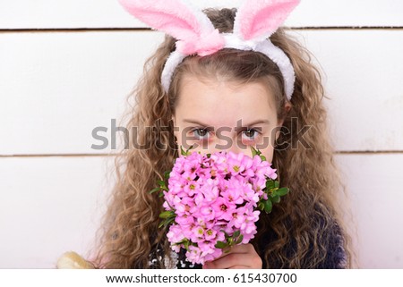cute girl in bunny ears, adorable happy small child with curly hair, pink flower bouquet on white wooden background, womens or mothers day spring holiday, greeting and celebration