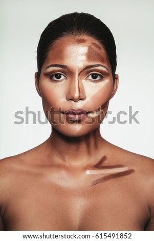 Close up portrait of young woman with contour and highlight makeup on face against white background. Female face with makeup highlighting and shading.