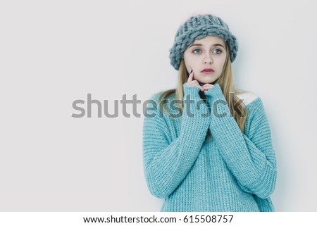 Pretty girl or cute young woman with blond hair and adorable face in fashionable blue sweater and hat isolated on white background, copy space