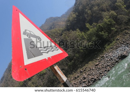 A way sign is a dangerous road. It is possible to drop the car into the river. A dangerous mountain road. Accident in the mountains.