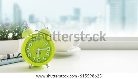 Morning concept. The table clock has a nice day with a cup of coffee and a newspaper flower pot, located near the window in a luxury apartment with city views in the morning.