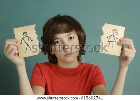 teenager boy hold mom and dad drawing in two torn paper pieces as a symbol of divorce close up sad portrait