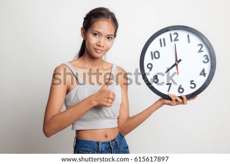 Young Asian woman thumbs up with a clock on white background