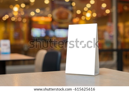 Mock up Label the blank menu frame in Bar restaurant ,Stand for booklets with white sheets paper acrylic tent card on wooden table cafeteria blurred background can inserting the text of the customer. Royalty-Free Stock Photo #615625616