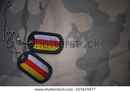 army blank, dog tag with flag of south ossetia on the khaki texture background. military concept