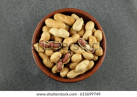 Peanuts in a wooden bowl on dark background.
