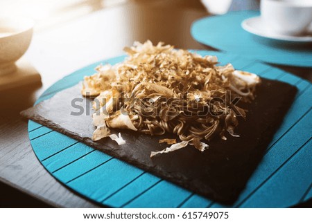 Buckwheat noodles with shrimps and shavings of tuna with sauce on black plate.food background.Eating concept.  Restaraunt place with wooden table. Flare copy space for text, design.