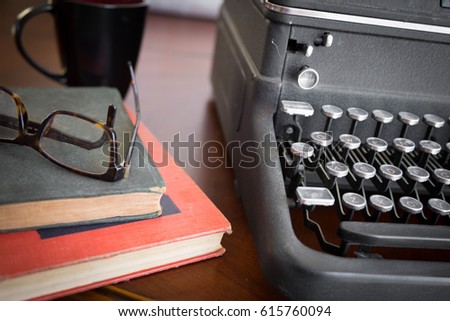 old black vintage typewriter sitting on wooden table next to old books, reading glasses, old letter with pen and quill. good for any author or writer with  creative dreams of journalism
