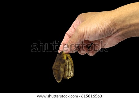 hand holding banana peel isolated on black background