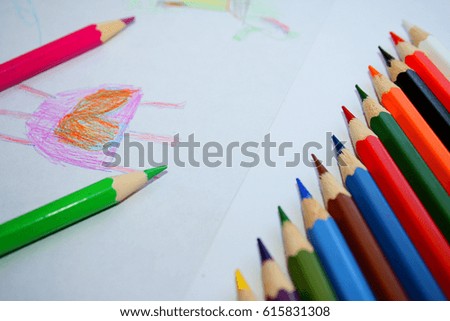 A palette of colors for children's pencils for drawing on paper and a child's drawing