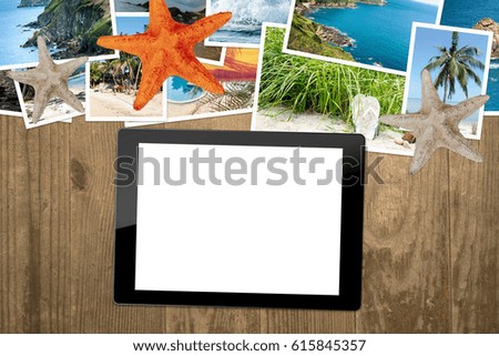 Tablet with blank screen and holiday photos on a wooden table. View from above and lie flat.