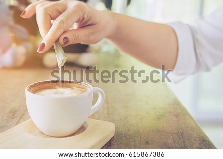Closeup of lady pouring sugar while preparing hot coffee cup Royalty-Free Stock Photo #615867386