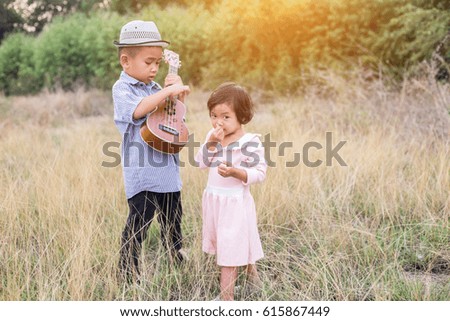Boy and his sister with a guitar in the meadow.