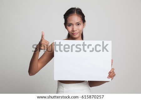 Young Asian woman show thumbs up with  white blank sign  on gray background