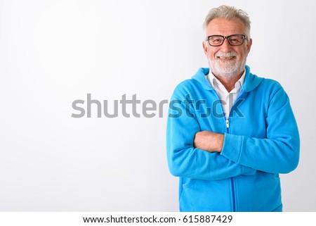 Studio shot of happy senior bearded man smiling with arms crossed ready for gym against white background