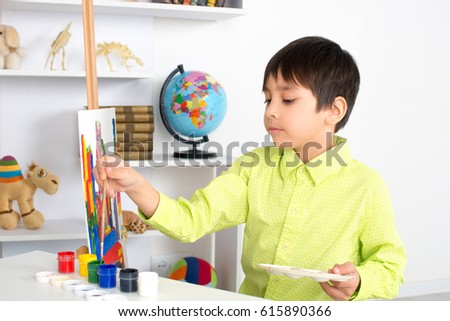 the boy draws on an easel paints