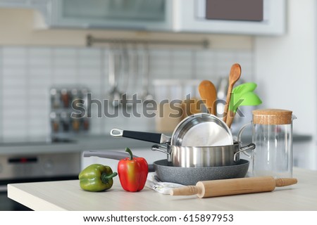 Kitchen utensils, cookware and peppers on wooden table Royalty-Free Stock Photo #615897953