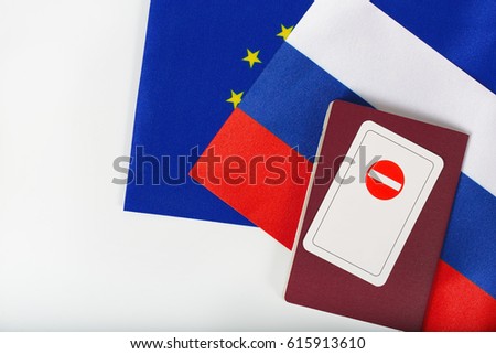 Card with a sign-access forbidden placed on a service passport of an international official. Two flags of EU and Russia in the background. Top view