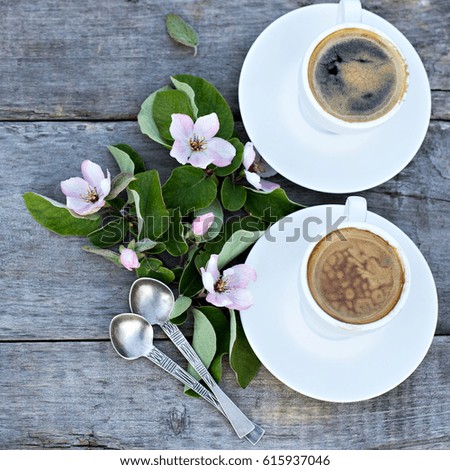 Coffee. Cups of espresso and spring flowers on a background of old wooden boards in sunshine. Rustic style.