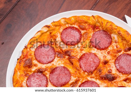 Top view of pizza with salami on a wooden background